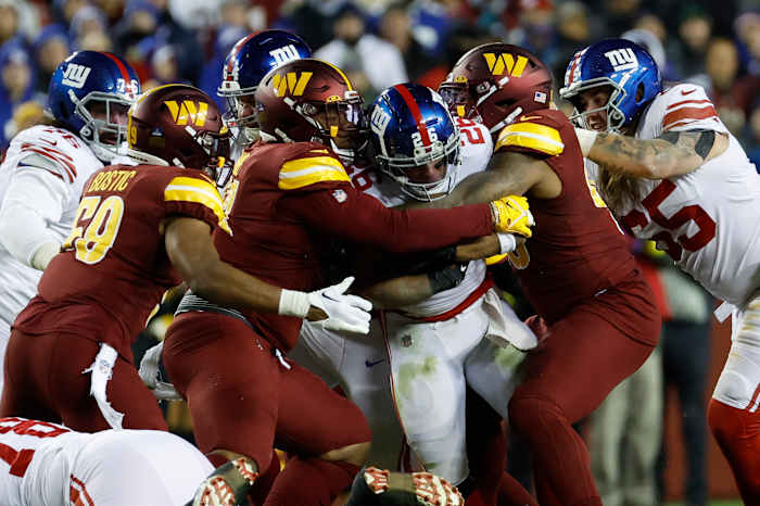 Washington Commanders defensive tackles Jonathan Allen (93) and Daron Payne (94) wrap up New York Giants running back Saquon Barkley during the third quarter at FedExField in 2022.